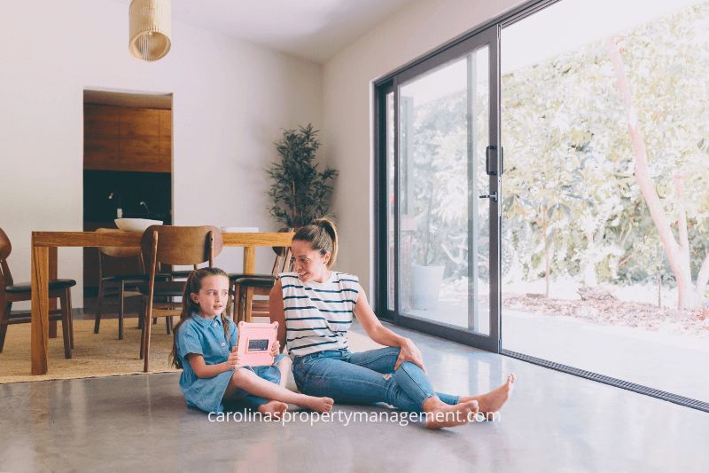 A mother and daughter sitting on the floor in their home, enjoying quality time together. This image highlights how Carolina Property Management LLC helps homeowners maintain a stable living environment while generating reliable rental income, unlike the unpredictable nature of Airbnb rentals.