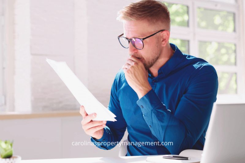 A concerned homeowner sitting at a desk, carefully reviewing documents. This image represents the thoughtful decision-making process involved in choosing the right rental strategy and highlights how Carolina Property Management Company offers a reliable alternative to Airbnb rentals, ensuring consistent income and less risk.