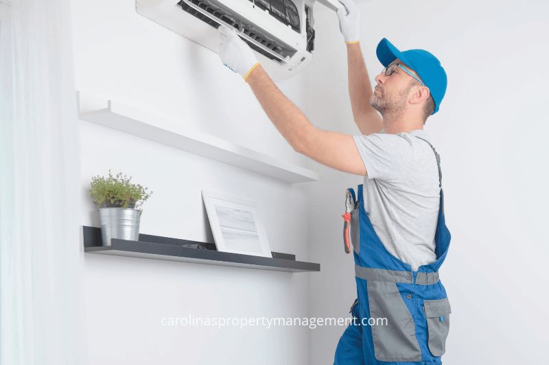 A professional technician performing air conditioning maintenance in a home. This image underscores how Carolina Property Management LLC handles regular maintenance and repairs for rental properties, providing hassle-free management for homeowners compared to the unpredictable maintenance needs of Airbnb rentals.