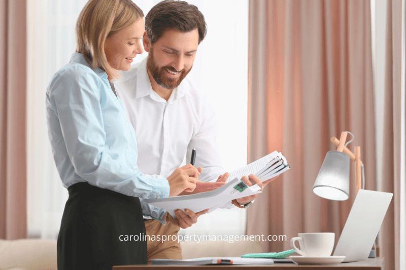 A young couple standing in a modern kitchen, discussing a tenant lease document. This image reflects the comprehensive leasing support provided by Carolina Property Management LLC, ensuring a smooth and informed rental process compared to Zillow’s platform.